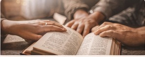 Hands gathered around an open Bible