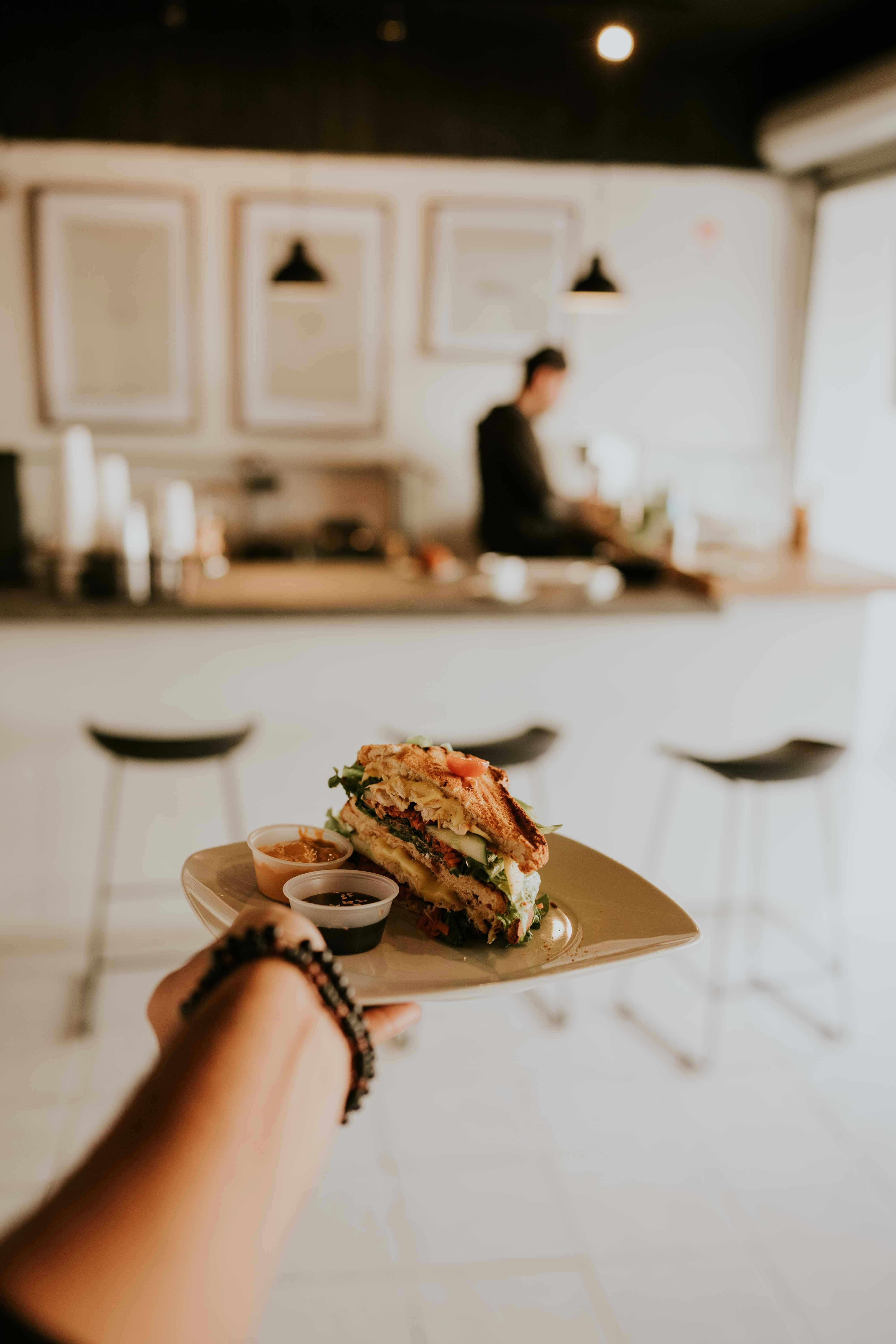 Fresh sandwich plate held in a bright café interior